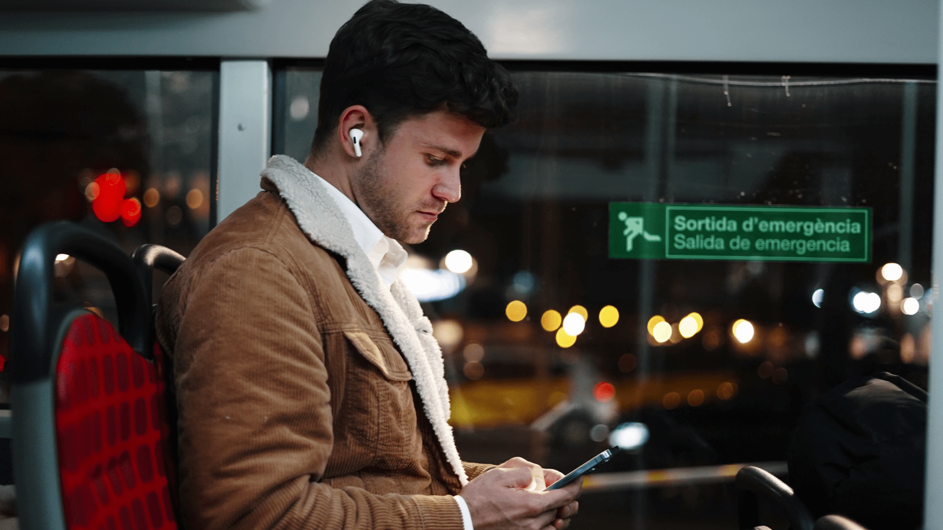 Chico sentado en un autobús mirando el móvil